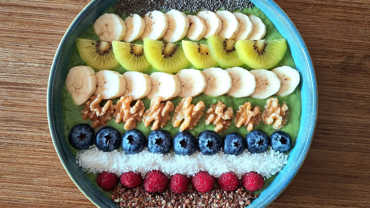 Vibrant smoothie bowl topped with assorted fruits, walnuts, and seeds, perfect for a healthy start.